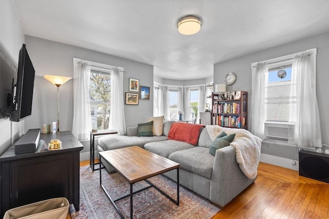 living area featuring cooling unit, a wealth of natural light, baseboards, and wood-type flooring