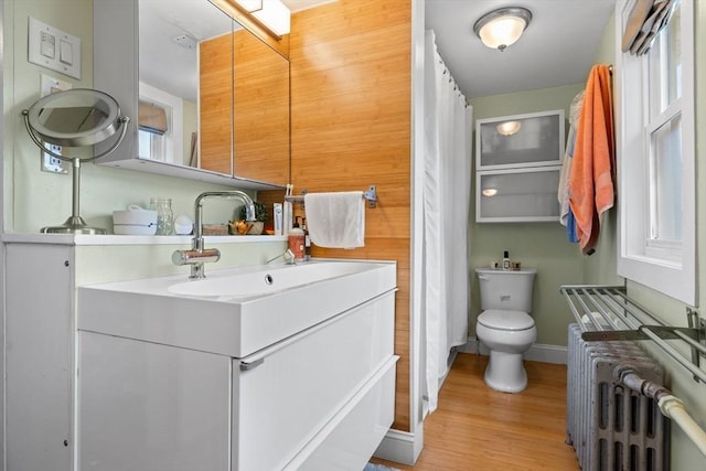 full bath featuring toilet, wood finished floors, radiator, baseboards, and vanity