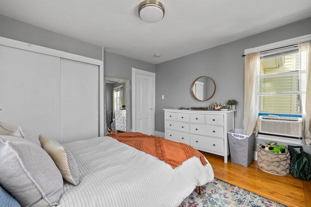 bedroom with cooling unit, a closet, and light wood-style floors