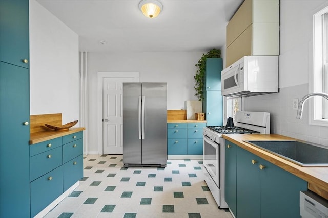 kitchen with a sink, butcher block counters, white appliances, and a wealth of natural light