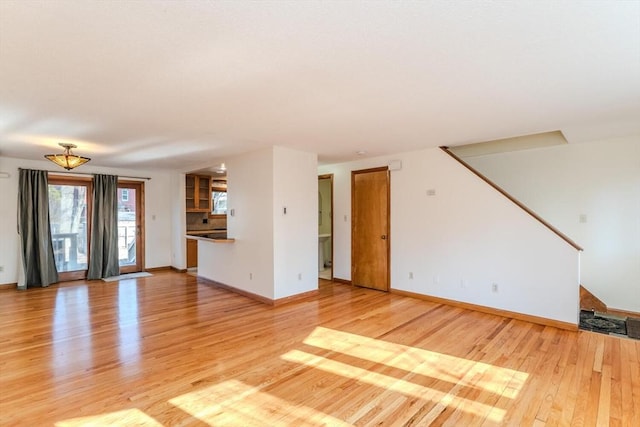 unfurnished living room featuring baseboards and light wood finished floors