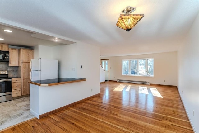 kitchen featuring tasteful backsplash, black microwave, baseboard heating, freestanding refrigerator, and electric range