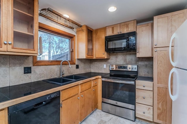 kitchen with a sink, decorative backsplash, glass insert cabinets, and black appliances