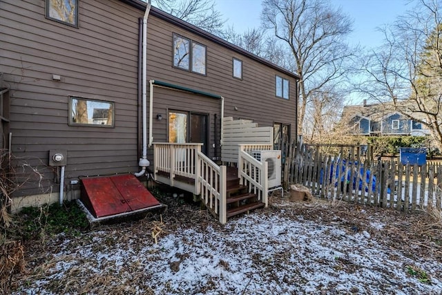 snow covered rear of property featuring fence