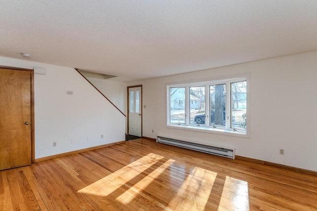 empty room featuring baseboards, light wood-type flooring, and a baseboard radiator