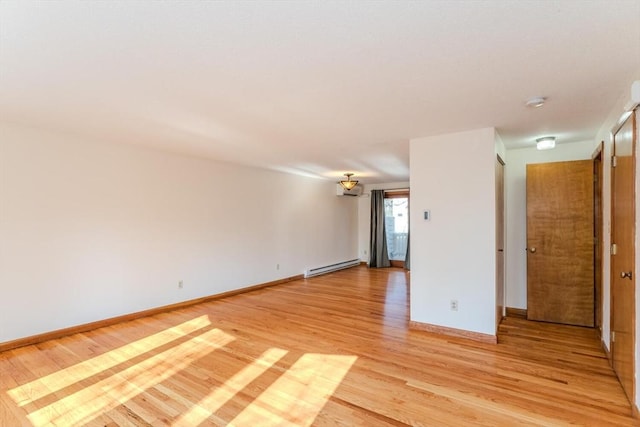 spare room featuring light wood-style flooring, baseboards, and baseboard heating