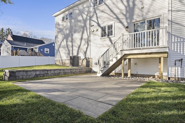 view of side of home with stairs, a yard, fence, and central air condition unit