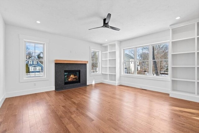 unfurnished living room with plenty of natural light, baseboards, and hardwood / wood-style floors