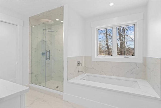 full bathroom with a garden tub, marble finish floor, a marble finish shower, and recessed lighting