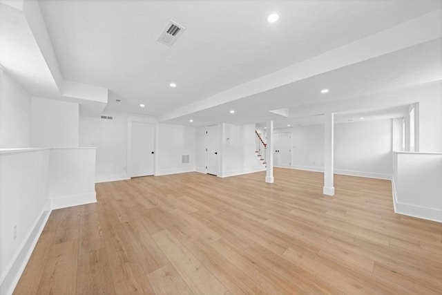 finished below grade area with recessed lighting, visible vents, baseboards, stairway, and light wood-type flooring