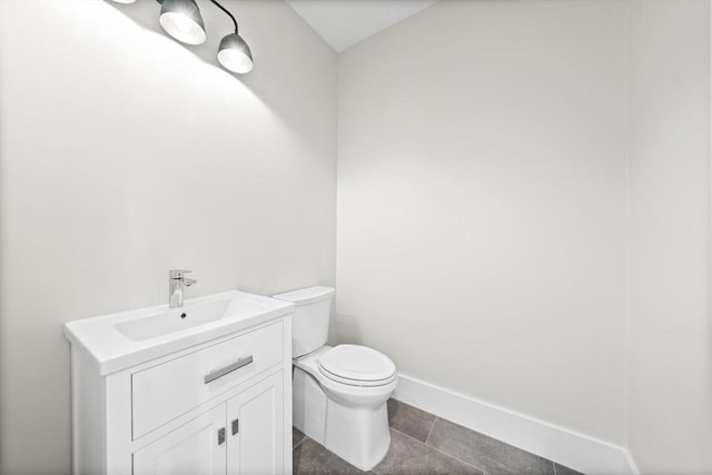 half bathroom featuring tile patterned flooring, baseboards, vanity, and toilet