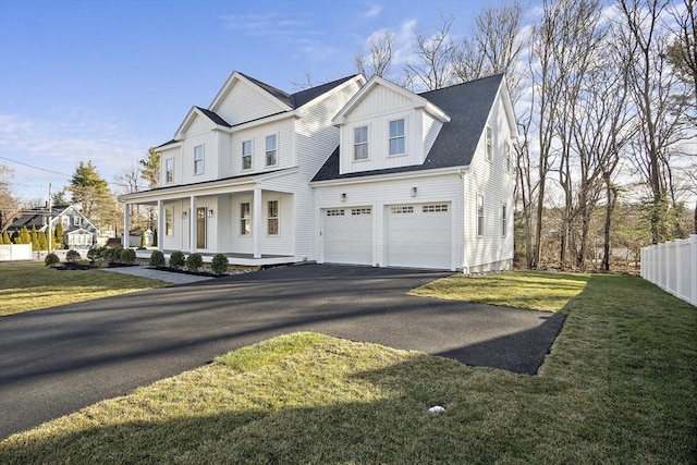 view of front of house featuring a porch, fence, a garage, driveway, and a front lawn