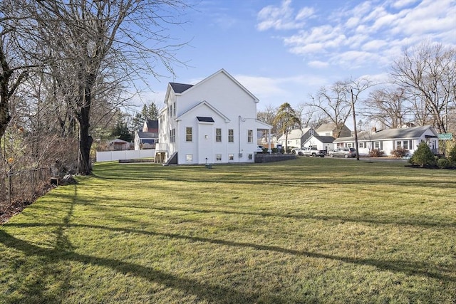 view of side of home with fence and a yard