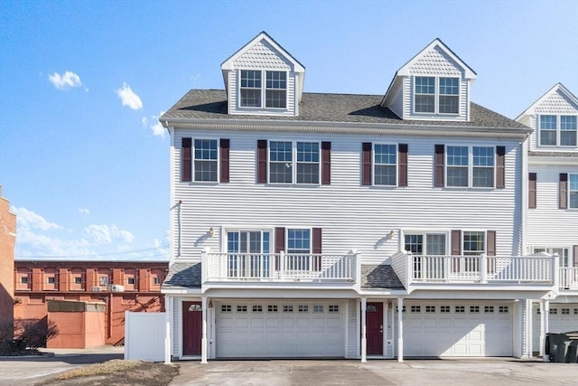 view of front of home featuring driveway, a balcony, a garage, and roof with shingles