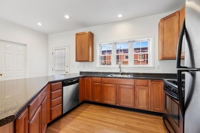 kitchen with recessed lighting, stainless steel appliances, a sink, light wood-type flooring, and brown cabinetry