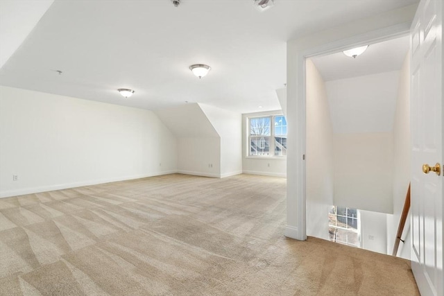 additional living space featuring lofted ceiling, baseboards, and light colored carpet