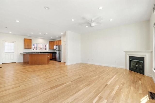 unfurnished living room featuring recessed lighting, a fireplace, a ceiling fan, baseboards, and light wood-type flooring