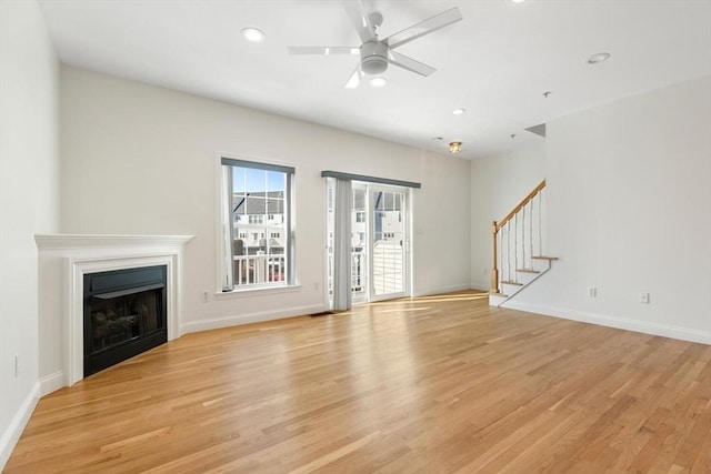 unfurnished living room with recessed lighting, a fireplace, baseboards, stairway, and light wood-type flooring