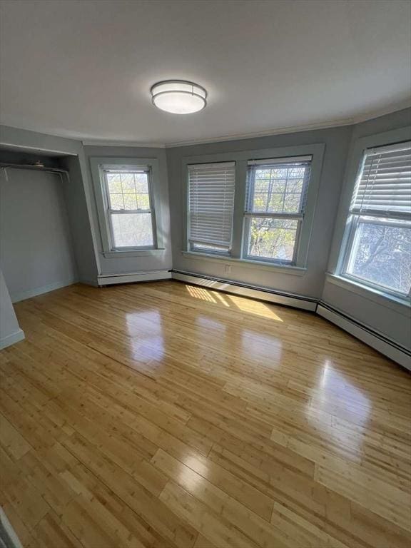 unfurnished dining area featuring plenty of natural light, crown molding, light wood-style floors, and baseboards
