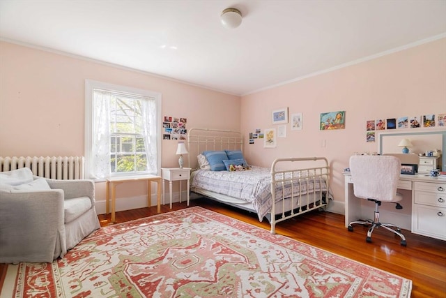 bedroom featuring crown molding, radiator heating unit, and wood finished floors