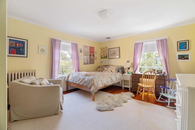bedroom with crown molding, wood finished floors, and radiator heating unit
