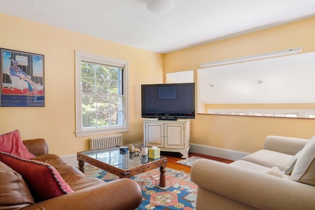 living room with radiator, baseboards, and wood finished floors