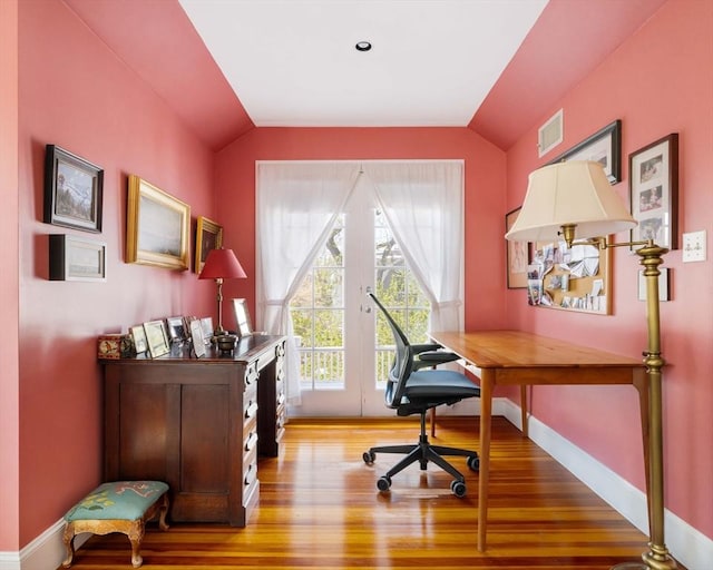 office space featuring visible vents, baseboards, lofted ceiling, and wood finished floors
