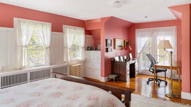 bedroom with radiator heating unit and wood finished floors