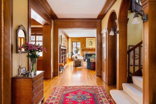 hallway with crown molding, light wood finished floors, and stairway