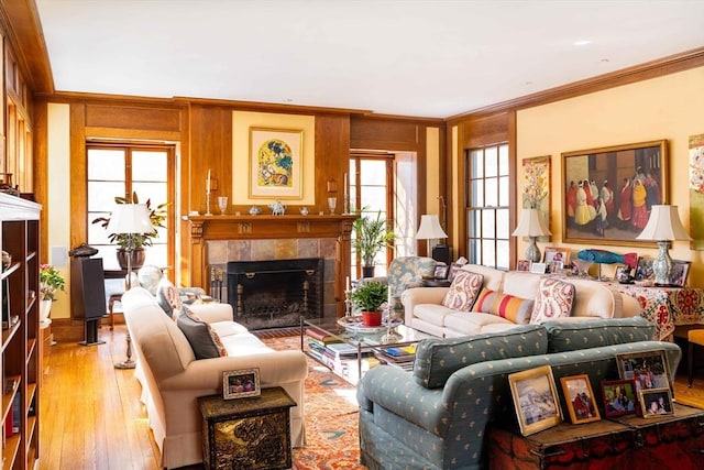 living room featuring crown molding, a tile fireplace, and light wood-style floors