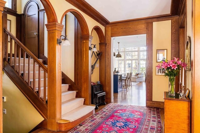 entrance foyer featuring stairs, arched walkways, ornamental molding, and wood finished floors