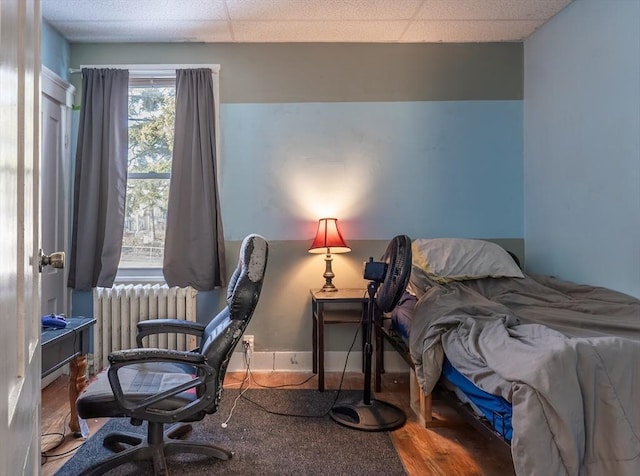 bedroom with hardwood / wood-style flooring, a paneled ceiling, and radiator