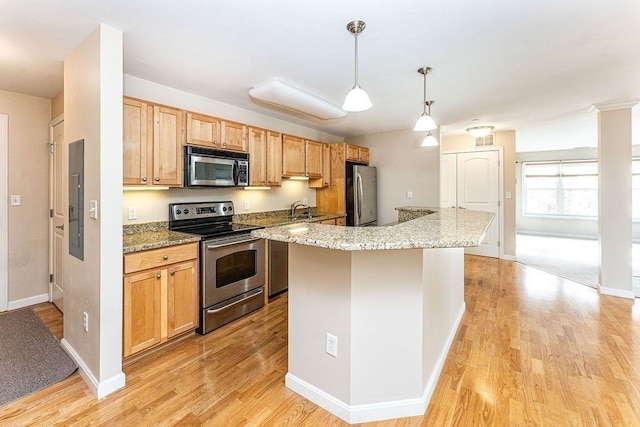 kitchen with light stone countertops, appliances with stainless steel finishes, pendant lighting, light hardwood / wood-style flooring, and a center island