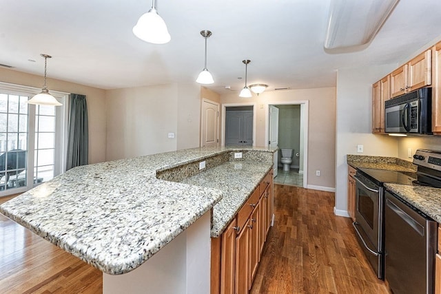 kitchen featuring light stone countertops, a kitchen island, decorative light fixtures, and appliances with stainless steel finishes