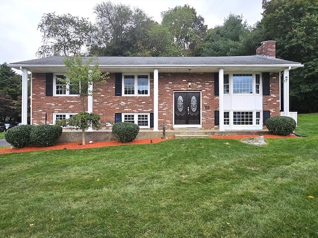 raised ranch featuring brick siding, a front lawn, and a chimney