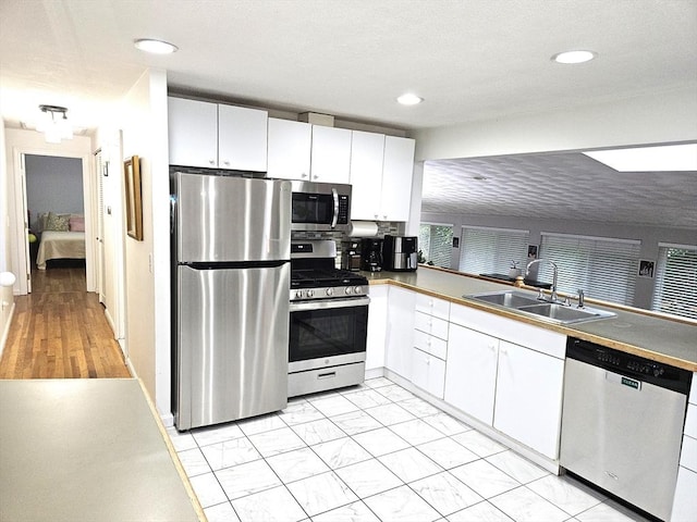 kitchen with a sink, appliances with stainless steel finishes, white cabinets, and recessed lighting