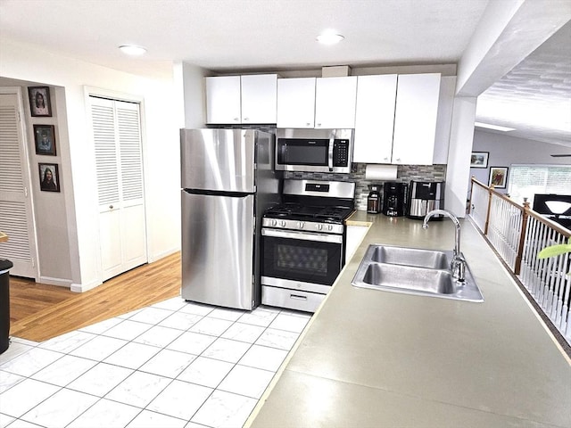 kitchen featuring a sink, light countertops, appliances with stainless steel finishes, white cabinetry, and tasteful backsplash