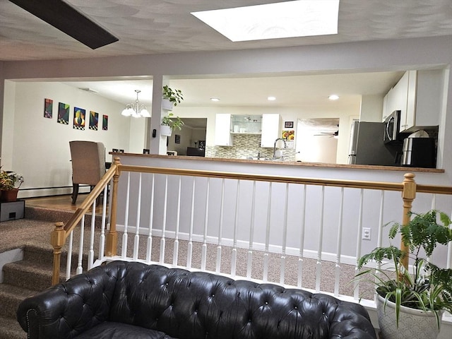 welcome area featuring stairway, a notable chandelier, a skylight, and a sink