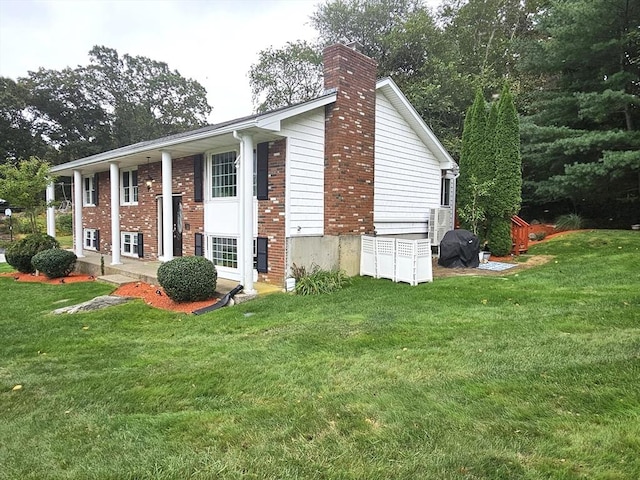 view of side of home featuring a yard, brick siding, and a chimney