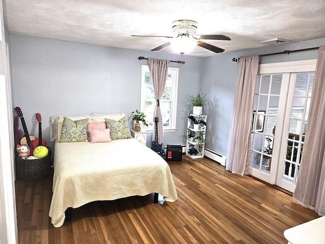 bedroom with wood finished floors, visible vents, ceiling fan, a textured ceiling, and baseboard heating