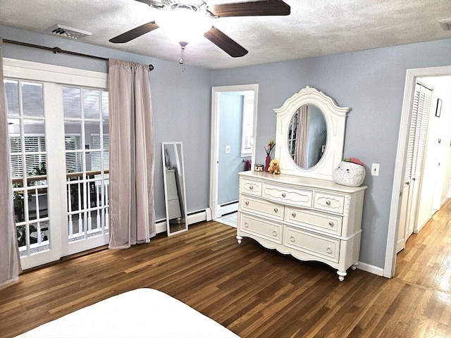 bedroom featuring dark wood finished floors, visible vents, a textured ceiling, and a baseboard radiator