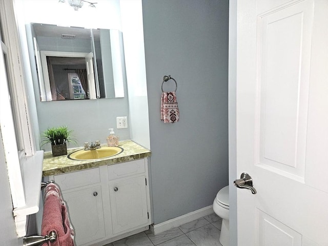 bathroom featuring baseboards, toilet, marble finish floor, and vanity