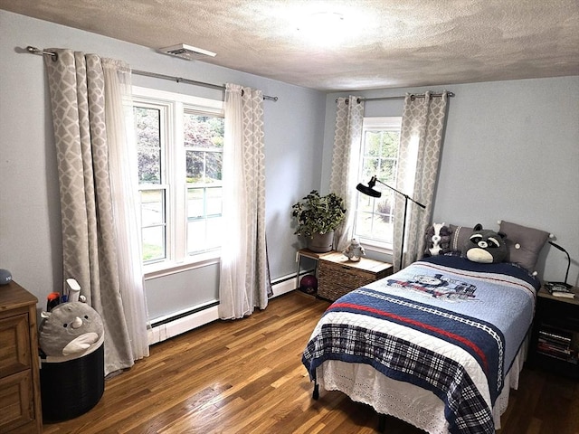 bedroom featuring wood finished floors, visible vents, baseboard heating, and a textured ceiling