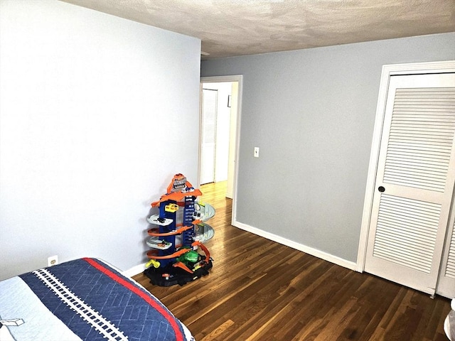 bedroom featuring dark wood-style floors, a textured ceiling, and baseboards