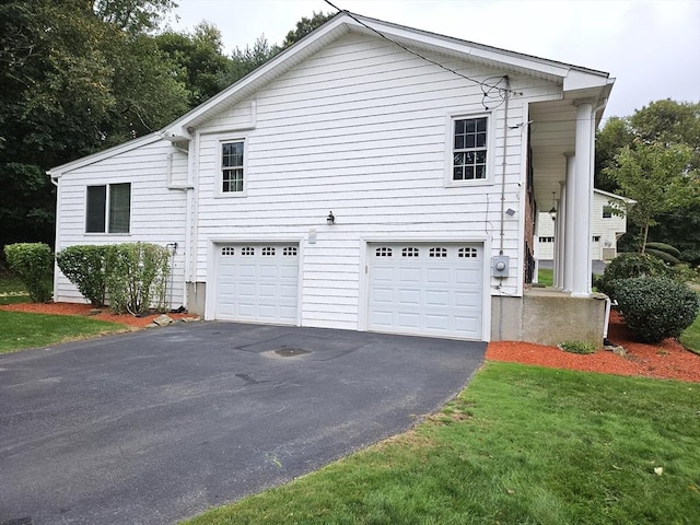 view of side of property with a yard, an attached garage, and driveway