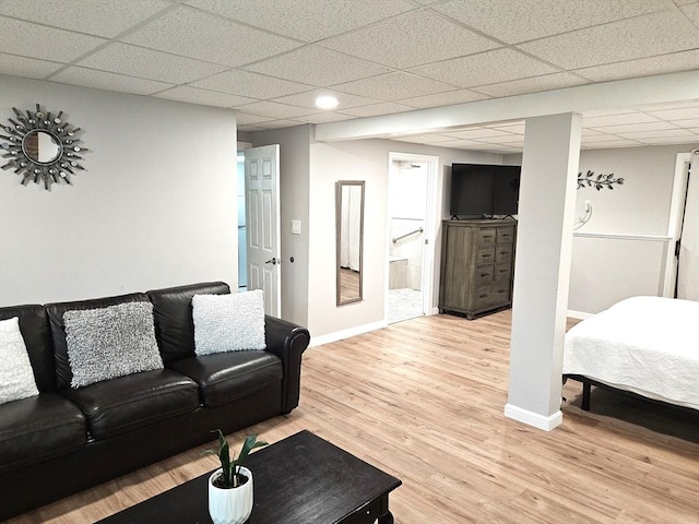 living room featuring a paneled ceiling, baseboards, and light wood-style floors