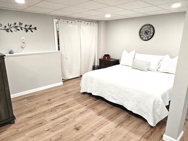 bedroom featuring wood finished floors, baseboards, and a paneled ceiling