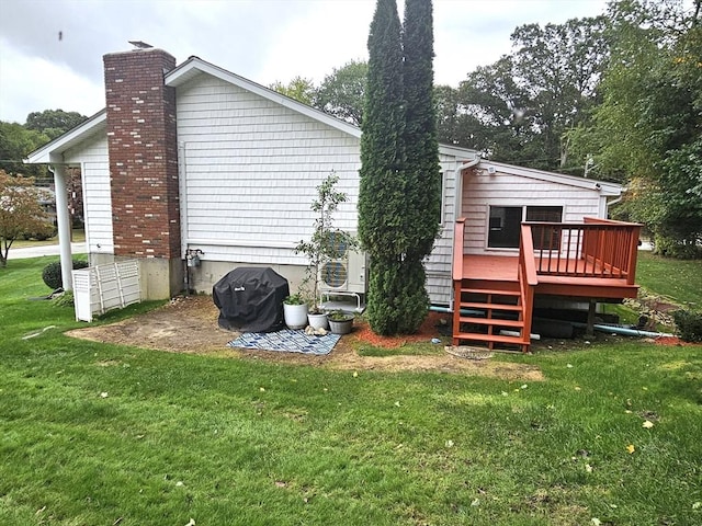 back of house with a lawn, a deck, and a chimney