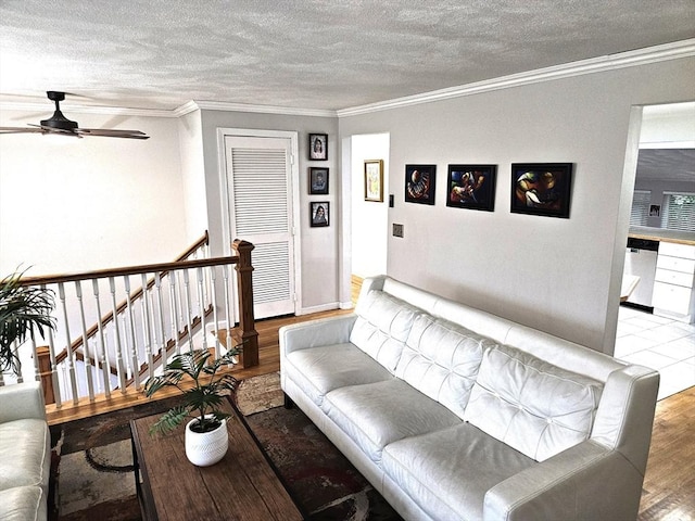 living area with a textured ceiling, crown molding, ceiling fan, and wood finished floors