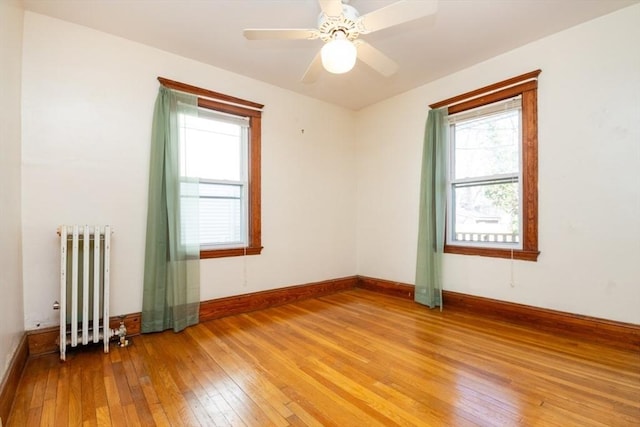 unfurnished room featuring light wood-style floors, baseboards, radiator, and ceiling fan